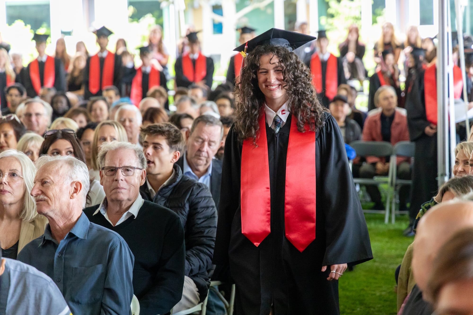 Estudiante sonriente con birrete y toga en su ceremonia de graduación en Canadá.