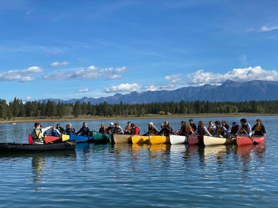 Grupo de estudiantes en canoas de colores sobre un lago de montaña de British Columbia.