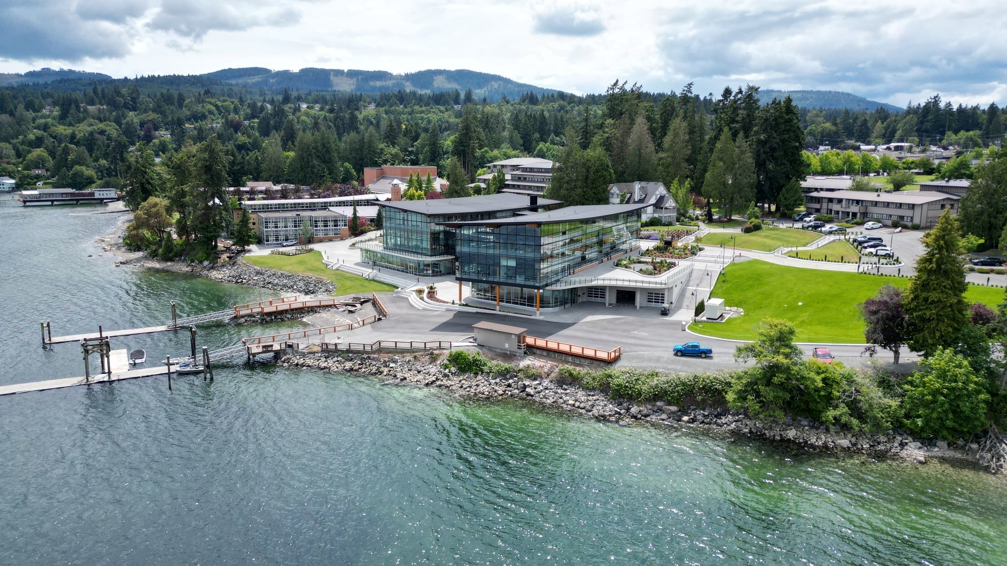 Campus moderno de un boarding school a orillas del mar, rodeado de bosque y montañas en British Columbia.