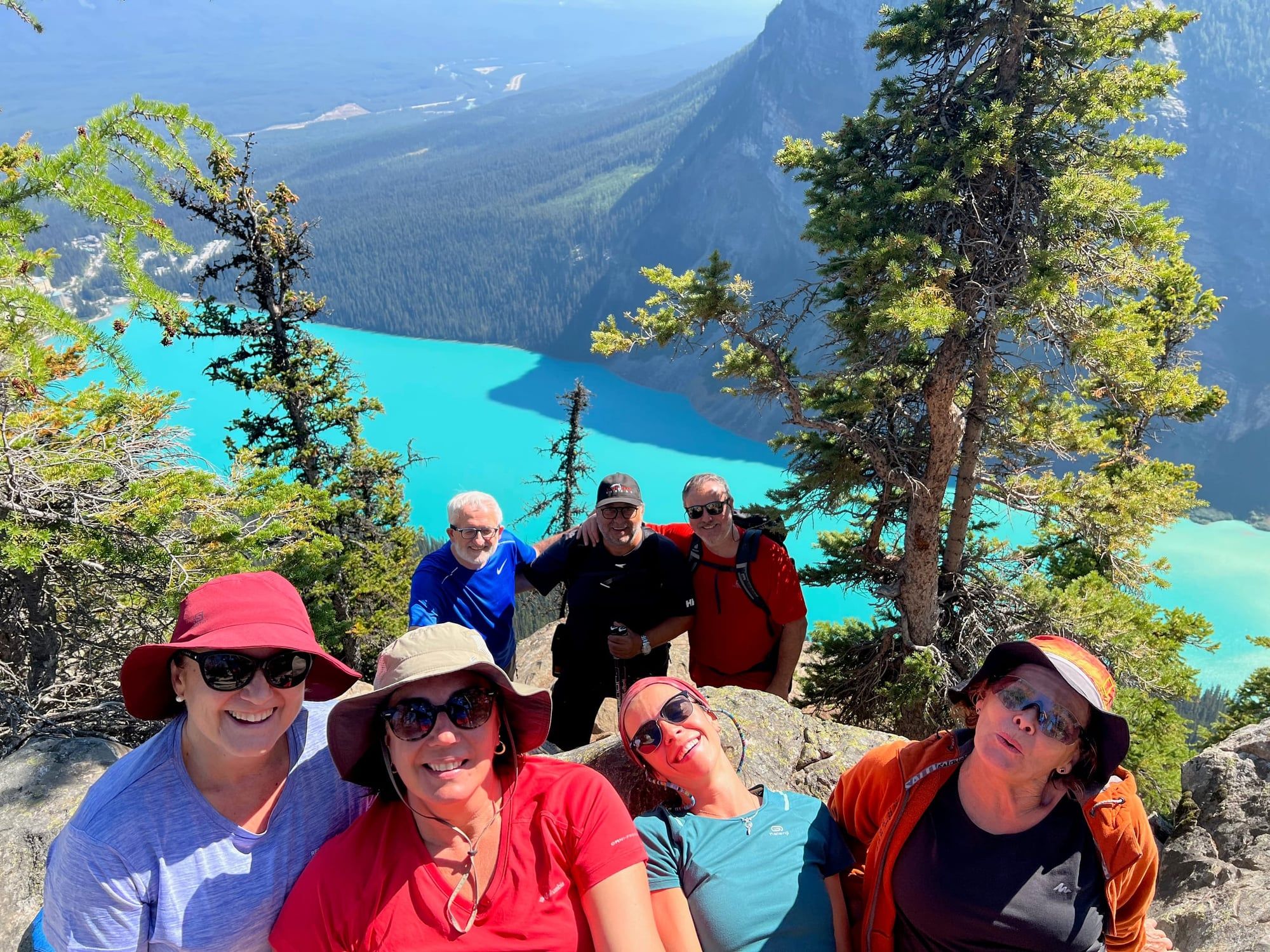 Un grupo de padres se hace un selfie en un mirador sobre un lago turquesa de montaña en Canadá.